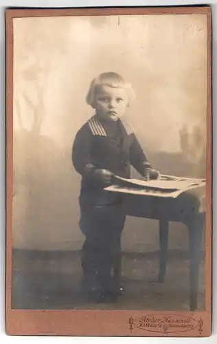 Fotografie Hermann Hauschild, Zittau i. Sa, Portrait kleiner Junge im Matrosenanzug mit Zeitung