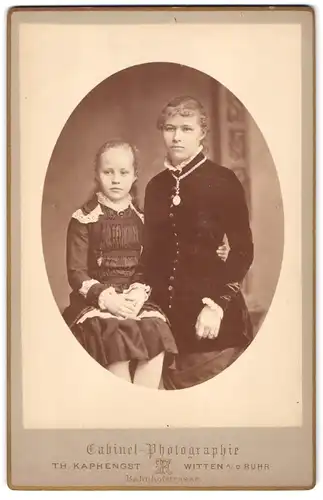 Fotografie Th. Kaphengst, Witten / Ruhr, Zwei junge Damen in dunklen Kleidern mit weissen Zierelementen