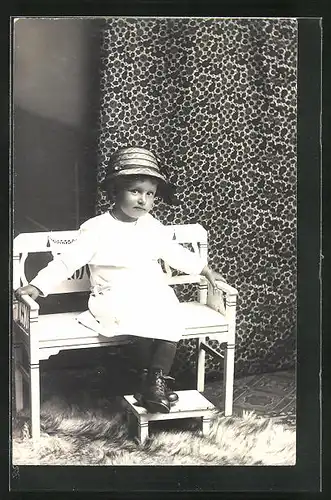 AK Kind sitzt wartend auf einer kleinen Bank