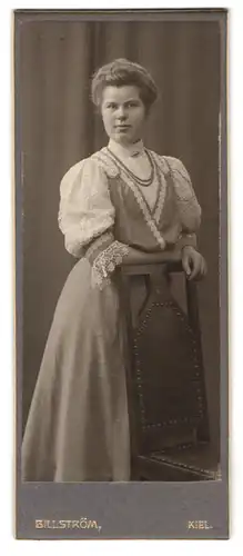 Fotografie Atelier Billström, Kiel, Holstenstrasse 43, Portrait hübsche junge Frau mit Halskette und Stickerei am Kleid