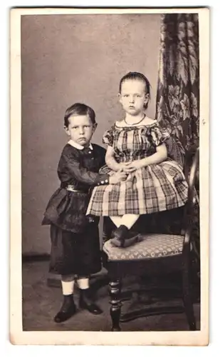 Fotografie unbekannter Fotograf und Ort, Portrait Wilhelm und Madelain Knoop in Kleidern auf einem Stuhl