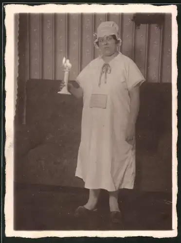 Fotografie Hausfrau im Nachthemd mit Schlafmütze und Kerzenständer