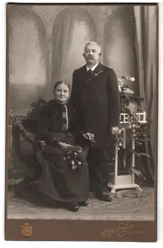 Fotografie Franz Spatzier, Trautenau, Neuhoferstrasse 19, Ehepaar im fortgeschrittenen Alter vor Pflanzenkulisse