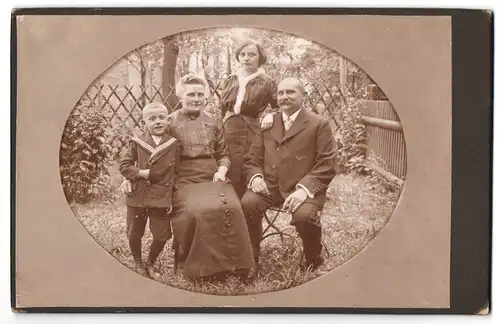 Fotografie unbekannter Fotograf und Ort, glückliche Familie im Garten mit Jüngstem in Matrosenanzug