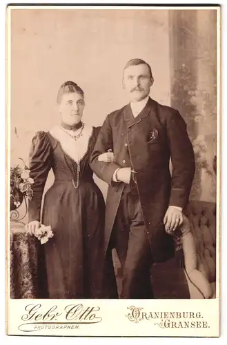 Fotografie Gebr. Otto, Oranienburg, Eheleute im Anzug und Biedermeierkleid mit Kette und Hochsteckfrisur