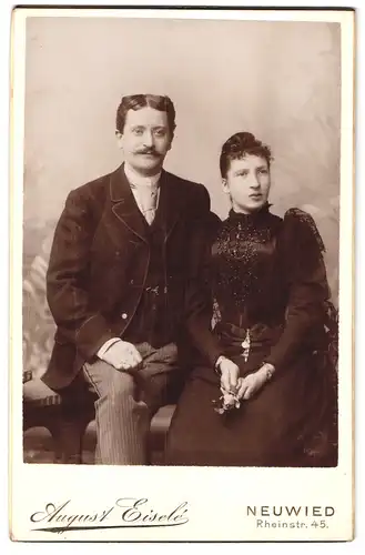 Fotografie August Eisele, Neuwied, Rheinstr. 45, Portrait Paar im Anzug mit Mittelscheitel und Kleid mit Locken