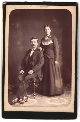 Fotografie unbekannter Fotograf und Ort, Portrait Paar im Anzug und Kleid mit Walrossbart und Locken