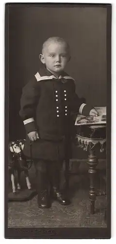 Fotografie H. Springmeier, Ort unbekannt, Portrait kleiner Junge im Matrosenrock mit Holzspielzeug