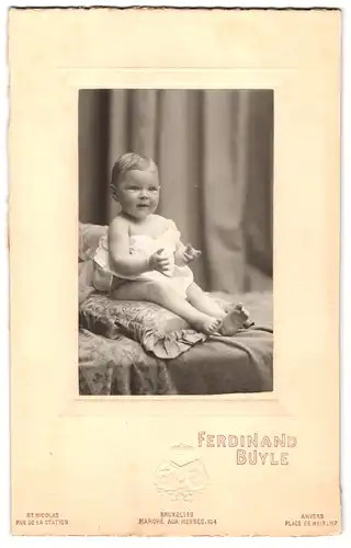 Fotografie Ferdinand Buyle, Bruxelles, Marché aux herbes 104, Kleinkind auf einem Kissen sitzend
