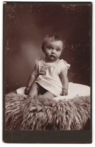 Fotografie Hermann Tietz, München, Bahnhofplatz, Portrait süsses Kleinkind auf Fell posierend