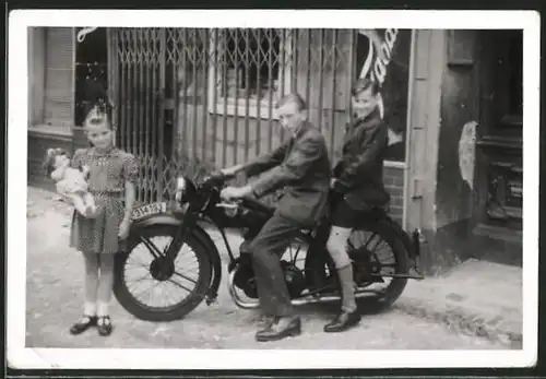 Fotografie Burschen auf Motorrad sitzend, Mädchen mit ihrer Puppe