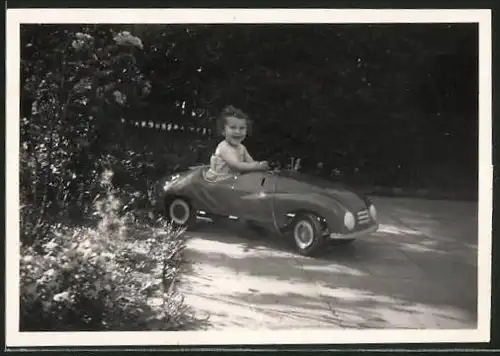 Fotografie Tretauto - Seifenkiste, glückliches Mädchen im Spielzeug-Auto