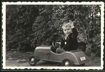 Fotografie Knabe im Tretauto - Seifenkiste winkt