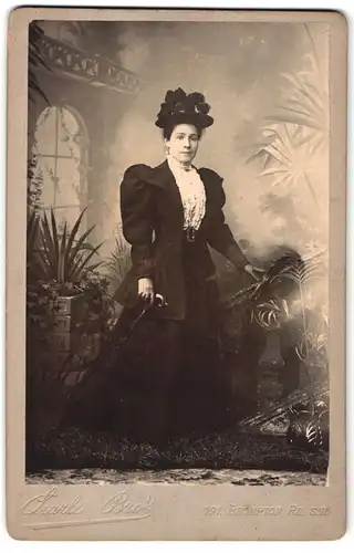 Fotografie Searle Bro's, London, 191 Brompton Road, Portrait hübsche Dame mit Hut im prachtvollen Kleid