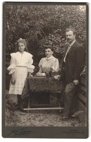 Fotografie Adolf Kühne, Wien, Burggasse 116, Portrait modisch gekleidetes Paar mit Tochter im Garten