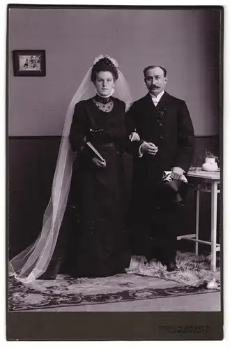 Fotografie Louis Schindhelm, Ebersbach i /S., Portrait junges Paar in Hochzeitskleidung mit Schleier und Buch