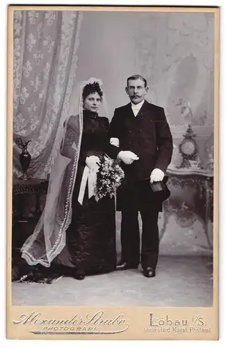 Fotografie Alex Strube, Löbau i /S., Portrait junges Paar in Hochzeitskleidung mit Schleier und Blumenstrauss