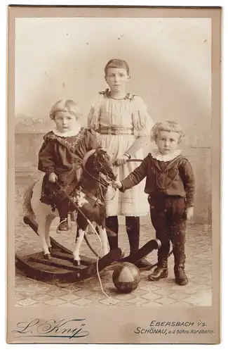 Fotografie L. Kny, Ebersbach i. S., neben Hotel Stadt Zittau, Portrait Kindern in Kleidern mit Schaukelpferd