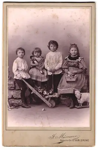 Fotografie J. Mürnseer, Karlsruhe, Rüppurrer-Str. 16, Portrait vier Kinder in Kleidern mit Puppe und Spielzeug Schaf