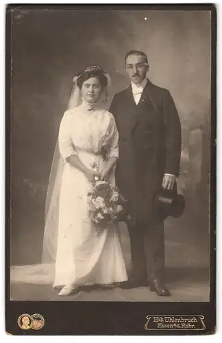 Fotografie Heinr. Uhlenbruch, Essen a /d. Ruhr, Portrait junges Paar in Hochzeitskleidung mit Schleier und Blumenstrauss