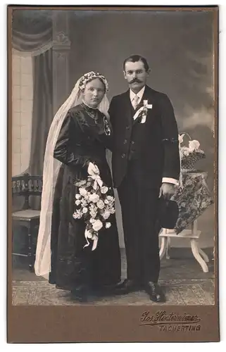 Fotografie Jos. Hinterwimer, Tacherting, Portrait junges Paar in Hochzeitskleidung mit Schleier und Blumenstrauss