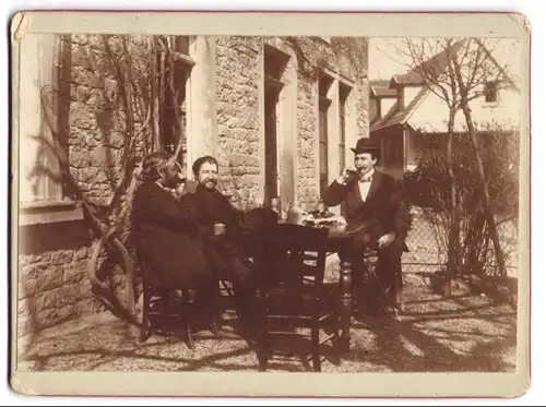 Fotografie unbekannter Fotograf und Ort, drei Herren in Anzügen beim Wein trinken im Garten