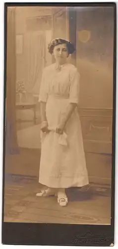 Fotografie Jul. Dürr, Bischofswerda i. S., Portrait junge Frau im weissen Kleid vor einer Studiokulisse