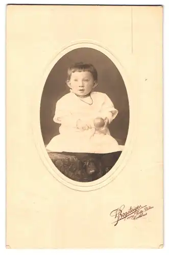 Fotografie F. Begsteiger, Cottbus, Portrait Kleinkind im weissen Kleid mit Perlenkette und Segelohren