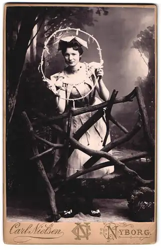 Fotografie Carl Nielsen, Nyborg, Torvet 7, Portrait Dame im Kostüm als Harlekin schaut durch einen Reifen