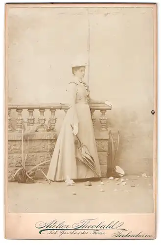 Fotografie Theobald, Fechenheim, Portrait Dame im hellen Kleid mit Hut und Schirm vor einer Studiokulisse