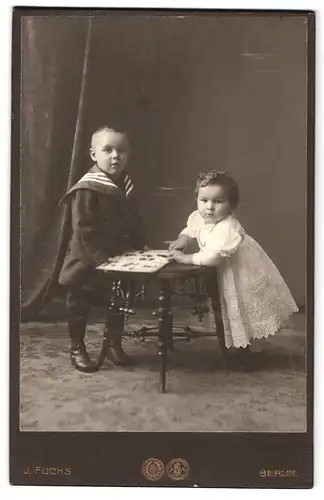 Fotografie J. Fuchs, Berlin, N.Friedrichstr. 108, Portrait zwei Kinder im Matrosenanzug und weissen Kleid im Atelier