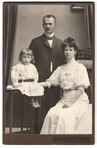 Fotografie Gebr. Pfusch, Wiesbaden, Rheinstr. 21, Portrait Mutter und Vater im Kleid und Anzug mit Tochter im Kleid