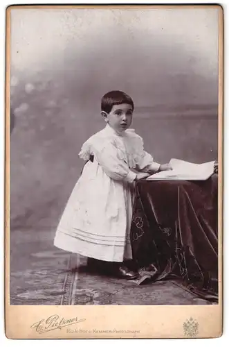 Fotografie C. Pietzner, Wien, Mariahilferstr. 3, Portrait Kleinkind im weissen Kleid liest in einer zeitung