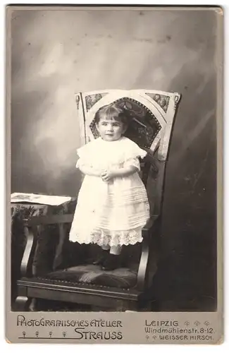 Fotografie Strauss, Leipzig, Windmühlenstr. 8-12, Portrait kleines Mädchen im weissen Kleid steht auf einem Stuhl