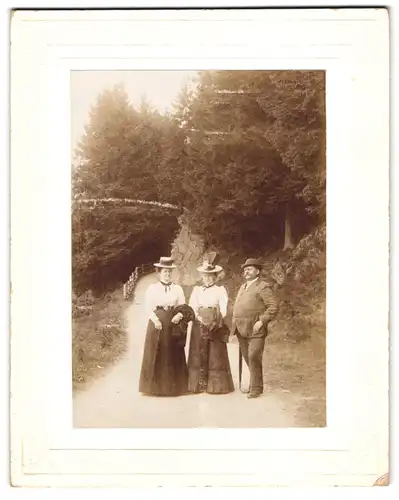 Fotografie Erwin Hoffmann, Braunlage / Harz, Portrait Herr im Anzug mit zwei Damen in Biedermeierkleidern und Hut