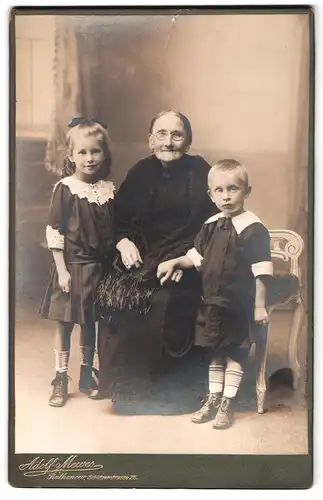 Fotografie Adolf Mewes, Rathenow, Schützenstr. 28, Portrait Oma im dunklen Kleid mit Ihren Enkelkindern in Kleidern