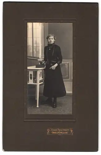 Fotografie Alwin Trautmann, Grossröhrsdorf, Portrait Mädchen im schwarzen Kleid mit Halskette und Fotoalbum im Atelier