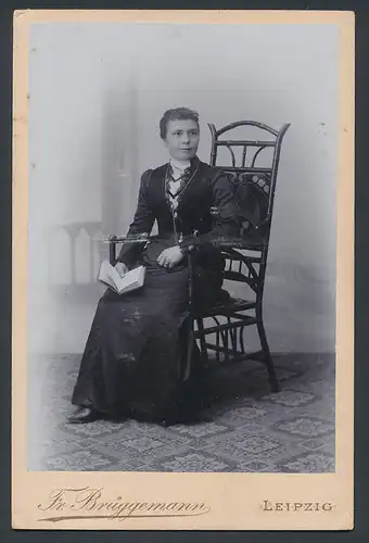 Fotografie Fr. Brüggemann, Leipzig, Eisenbahnstr. 1, Portrait Frau im Biedermeierkleid sitzt im Stuhl mit Buch in Hand