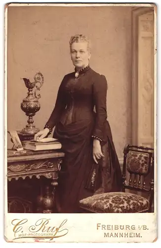 Fotografie C. Ruf, Freiburg i. B., Ludwigstr. 2, Portrait Dame im schwarzen Biedermeierkleid mit Fächer und Brosche