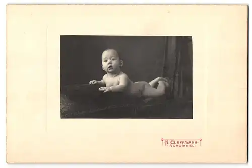 Fotografie H. Cleffmann, Vohwinkel, Portrait nackiges Baby bäuchlings auf Kissen liegend