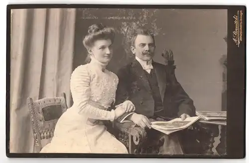 Fotografie A. Sternitzki, Braunschweig, Steinweg 10, Portrait modisch gekleidetes Paar mit Zeitung