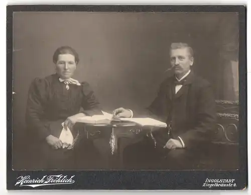 Fotografie Heinrich Fröhlich, Ingolstadt, Ziegelbräustrasse 4, Portrait elegantes Paar mit Buch und Zeitung am Tisch