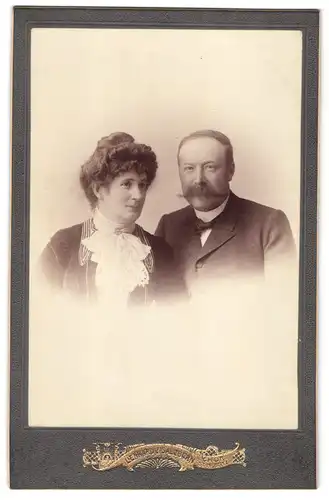 Fotografie Lienhard & Salzborn, Chur, Neben der Post, Portrait Mann im Anzug mit Walrossbart und Frau im Kleid