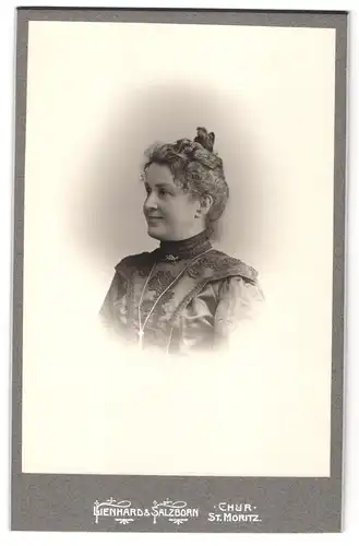 Fotografie Lienhard & Salzborn, Chur, Portrait Dame im bestickten Kleid mit Halskette und Hochsteckfrisur