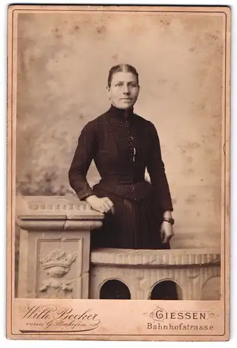 Fotografie Wilh. Becker, Giessen, Bahnhofstr., Portrait Dame im dunklen Biedermeierkleid in einer Studiokulisse