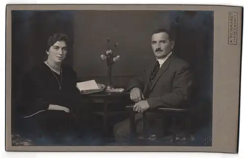 Fotografie A. Reinhardt, Sissach, Portrait Eheleute mit Buch am Tisch sitzend