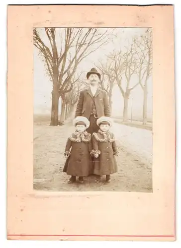 Fotografie unbekannter Fotograf und Ort, Portrait Vater mit Zwillingen in Herbstmänteln auf einer Allee