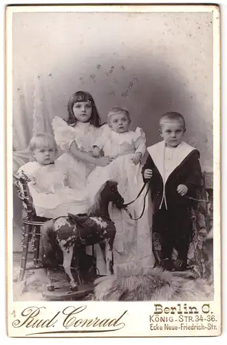 Fotografie Rud. Conrad, Berlin, König-Str. 34-36, Portrait Kinder in Kleidern mit Schaukelpferd