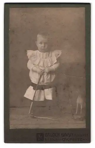 Fotografie Brüder Hahn, Chemnitz, Königstrasse 21, Portrait kleines Mädchen im Kleid mit Peitsche und Spielzeugpferd