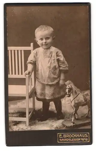 Fotografie E. Brockhaus, Gardelegen, Portrait kleines Mädchen im Kleid mit Spielzeugpferd